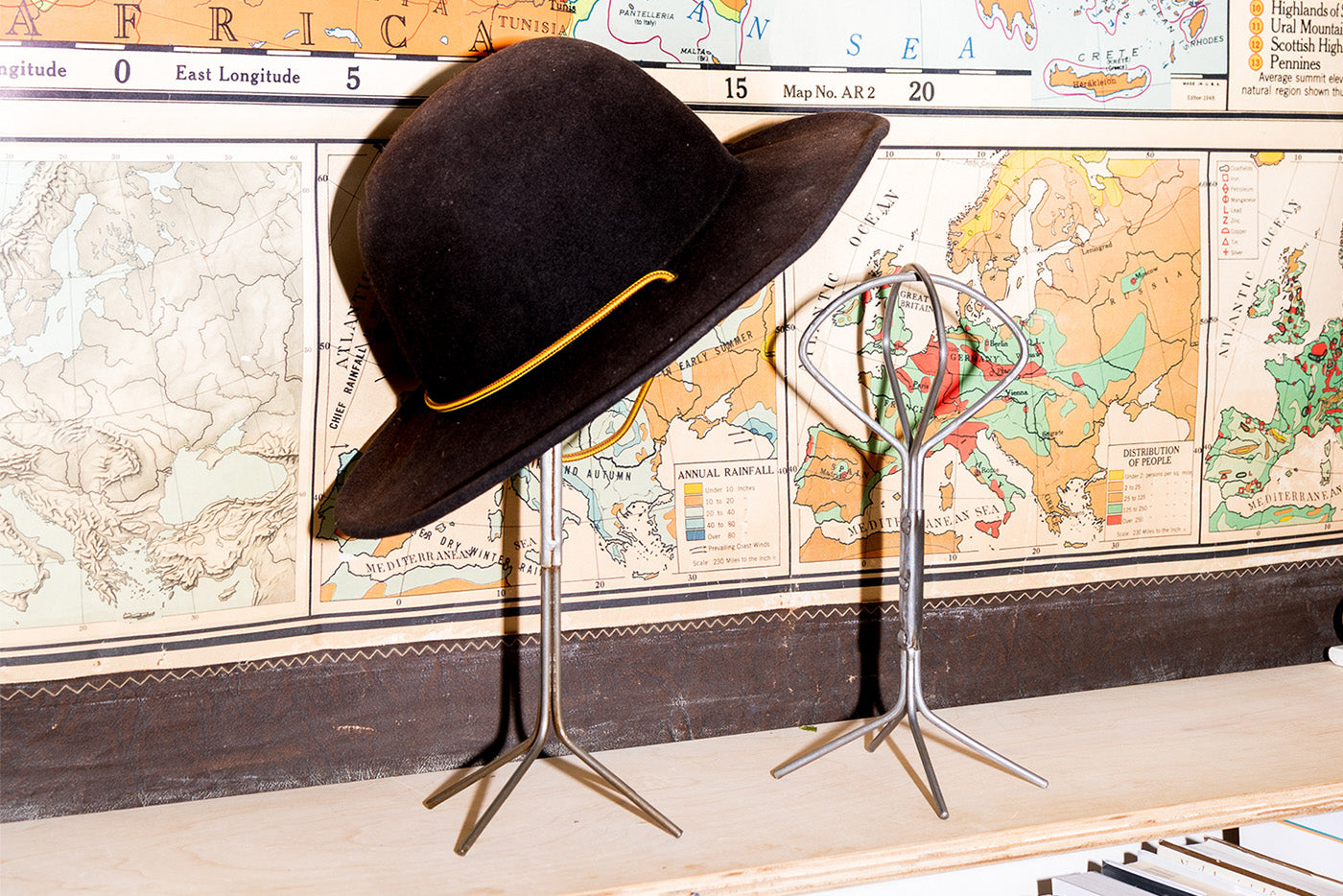 world Map background with 2 Puebco hat holders with a brown hat on one